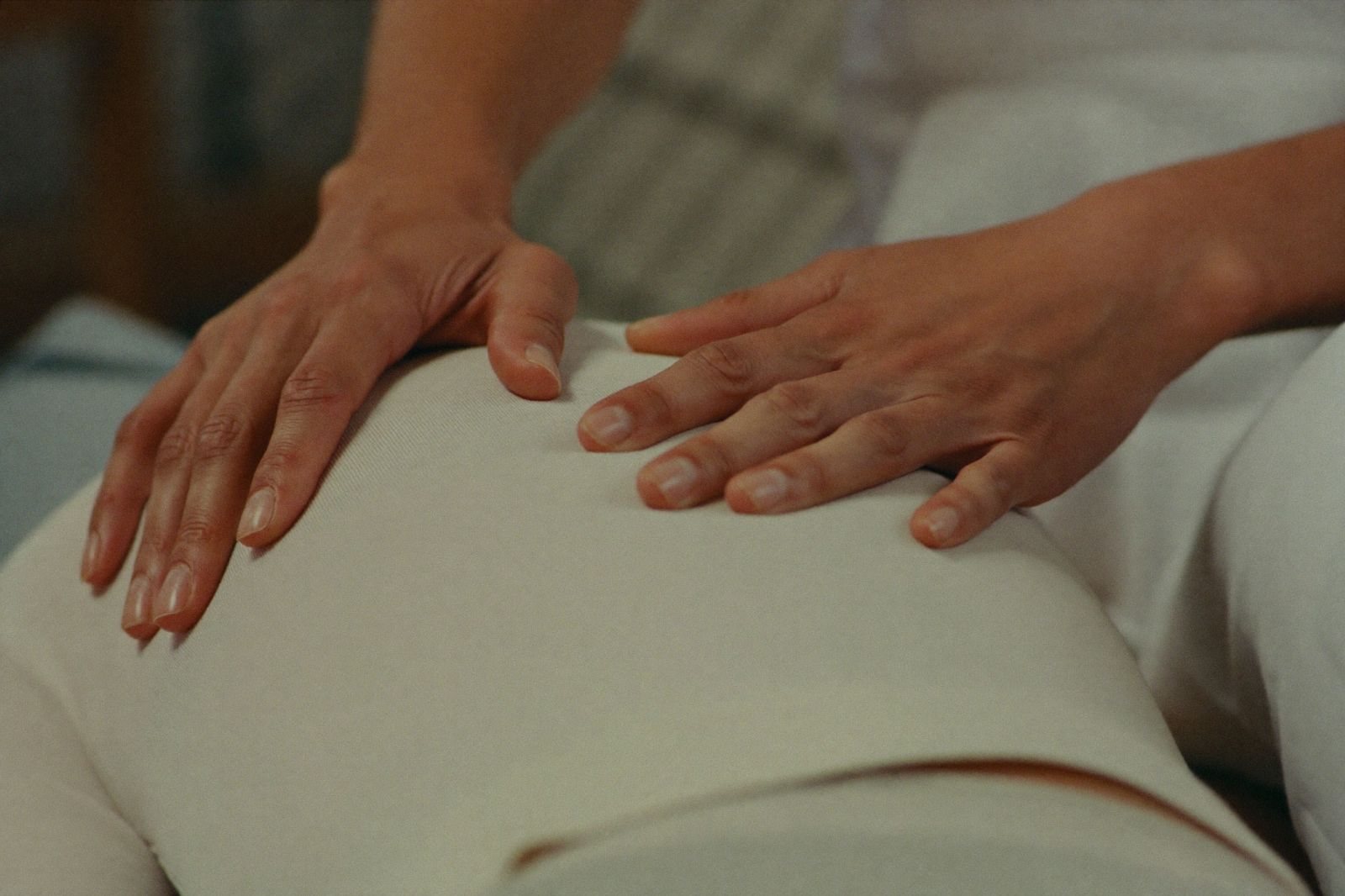 Practitioner hands resting with calm precision on a patient's back