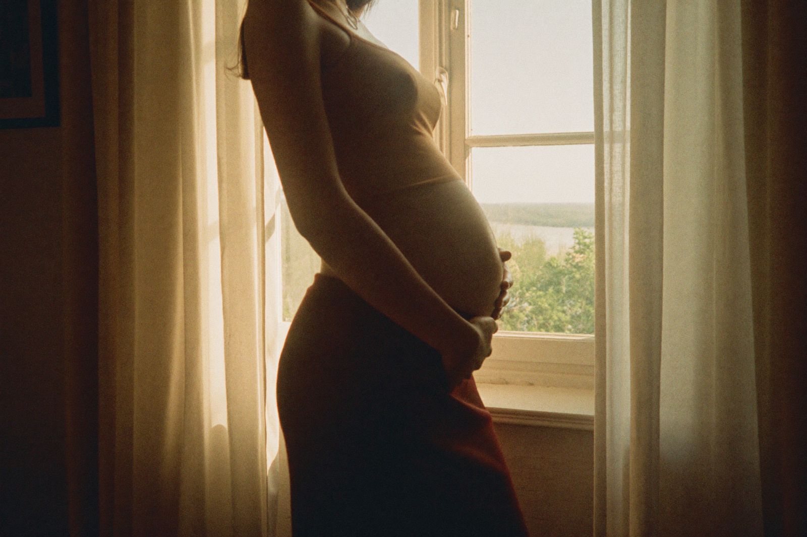 An expectant mother standing in soft window light
